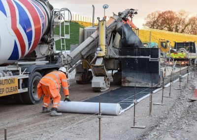 Rolling out geotextile membrane under surface water channel drain(116)